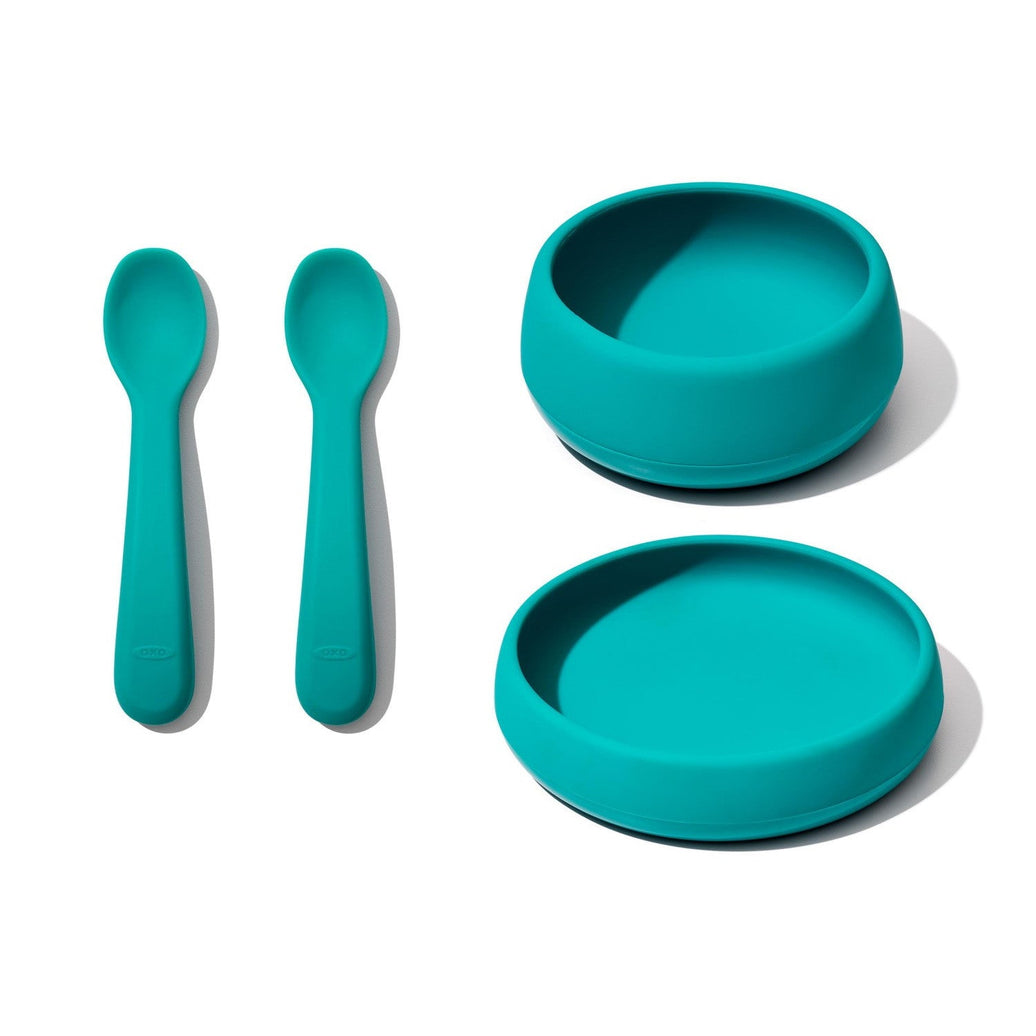 "Blauwgroen kinderservies met kom, bord en twee lepels van veilig silicone, ideaal om zelfstandig leren eten te stimuleren."